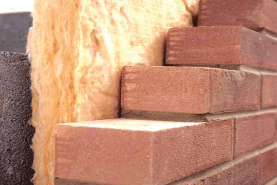 A cross-section of a wall showing cavity wall insulation being installed